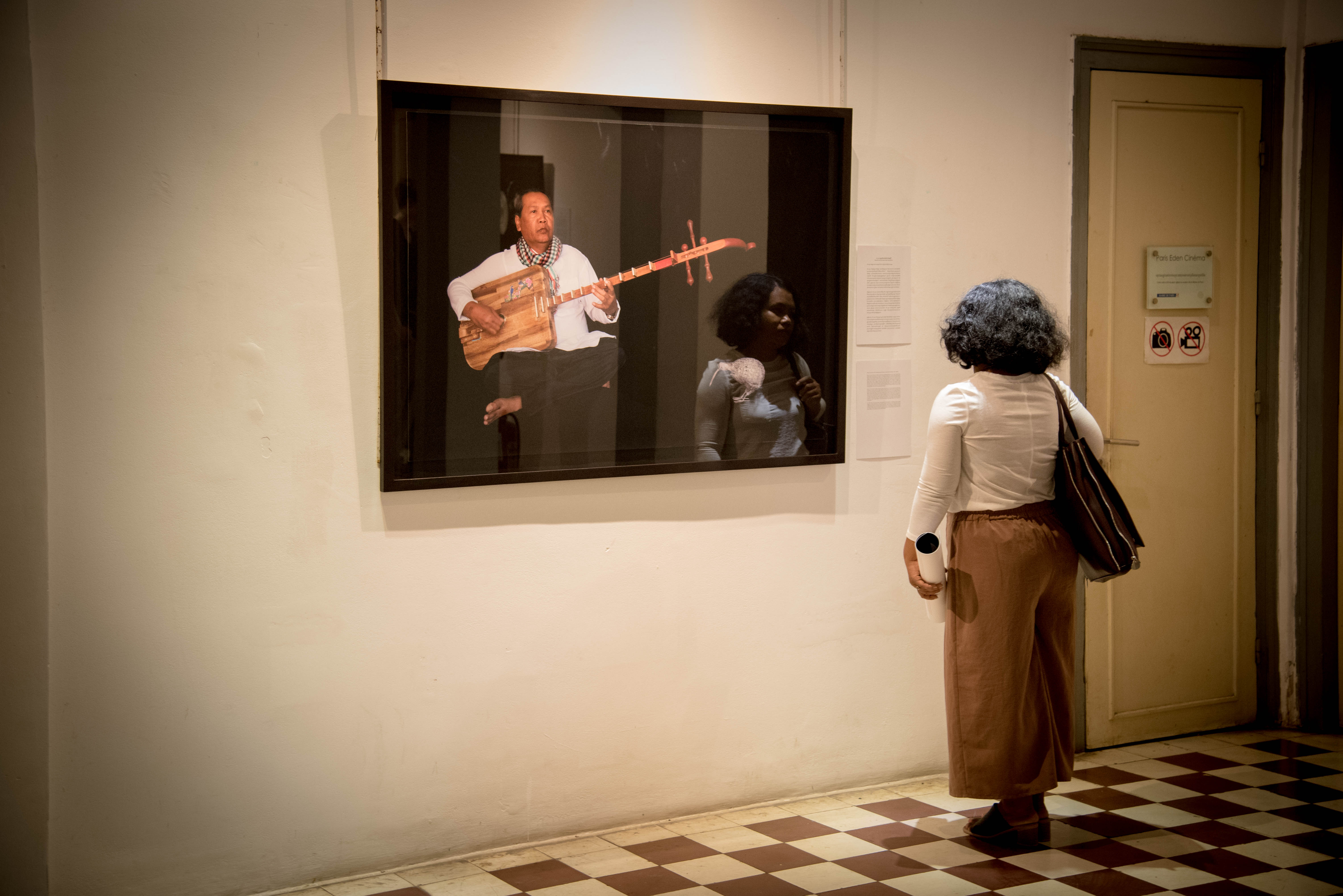 Slider Image A visitor examines Kim Hak's image of former refugee and musician, Hearn On.