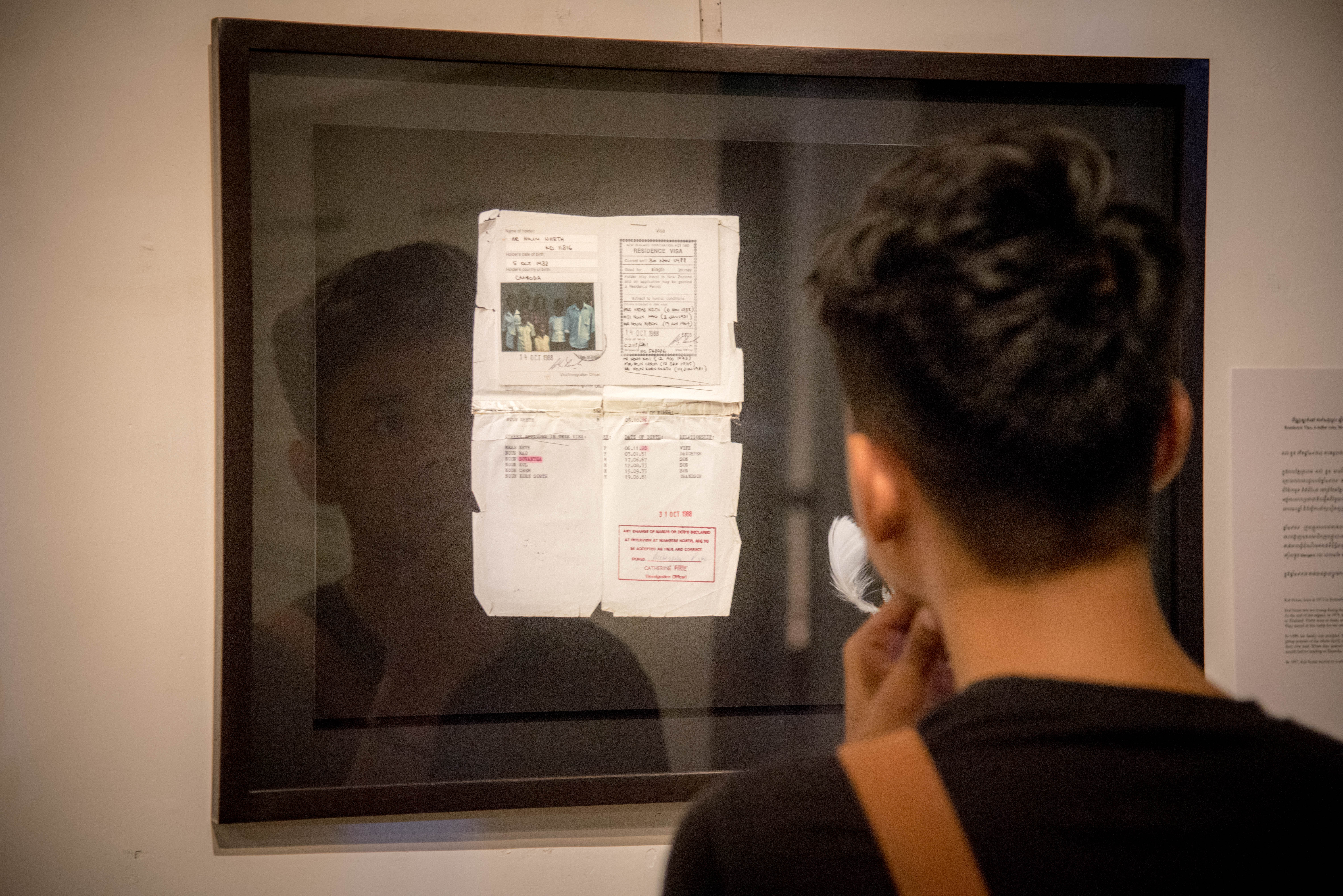 A visitor to the exhibition considers Kim Hak's image of refugee documentation of one of the Auckland-based participants in the project. 